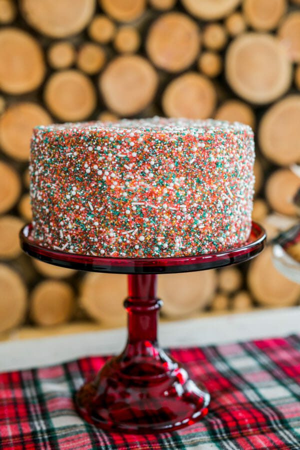 My Holiday Sprinkle Cake is super easy, but festive! Add a pop of color to holiday dessert table with this DIY holiday cake! || JennyCookies.com #sprinkcake #christmascake #cakedecorating #holidaydesserts