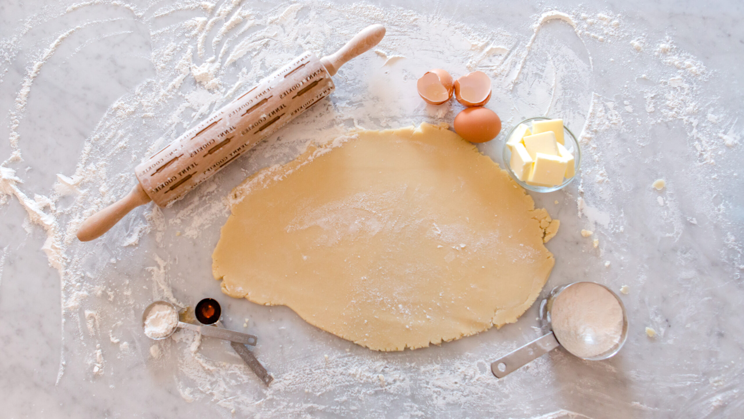 sugar cookie dough rolled out on floured surface