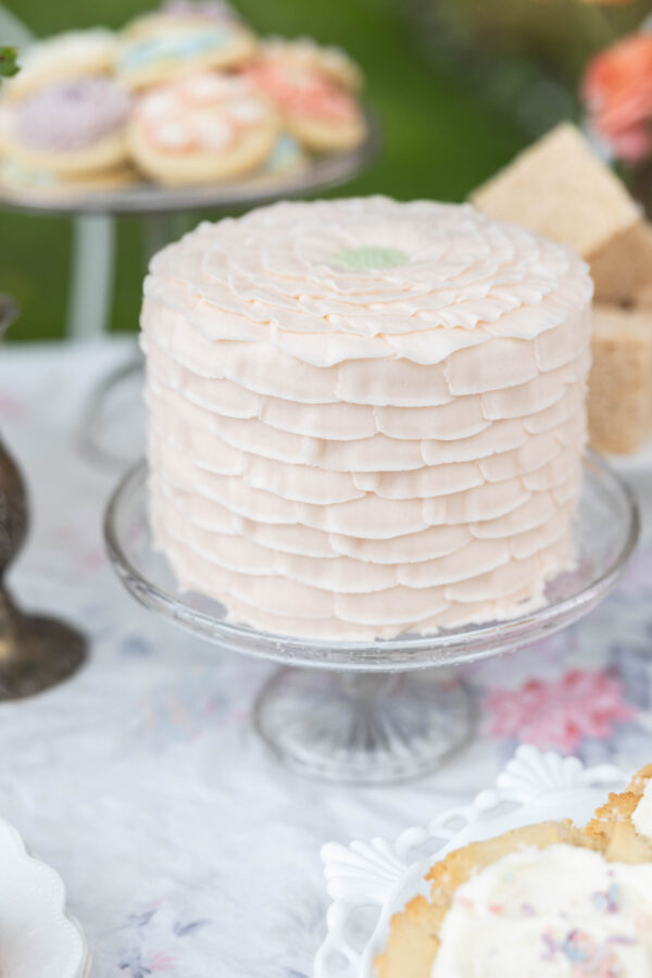 pale pink cake with petals piped onto it to look like a flower, on a cake stand